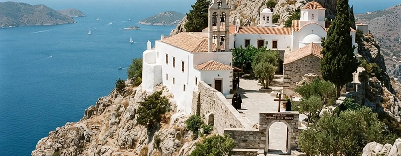 A whitewashed monastery on a rocky ridge above the sea on Hydra.