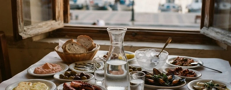 Meze plates and a carafe of tsipouro on a tsipouradiko table in Volos