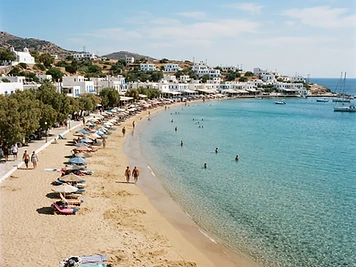 The long sandy curve of Platis Gialos beach on Sifnos with tamarisk trees behind.