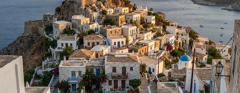 The old hilltop Chora of Alonissos, stone and whitewashed houses around a ruined castle in the evening light.