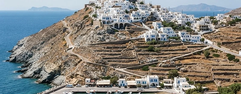 The white village of Serifos on its hill above the small port, with dry stone terraces and a sandy bay below.