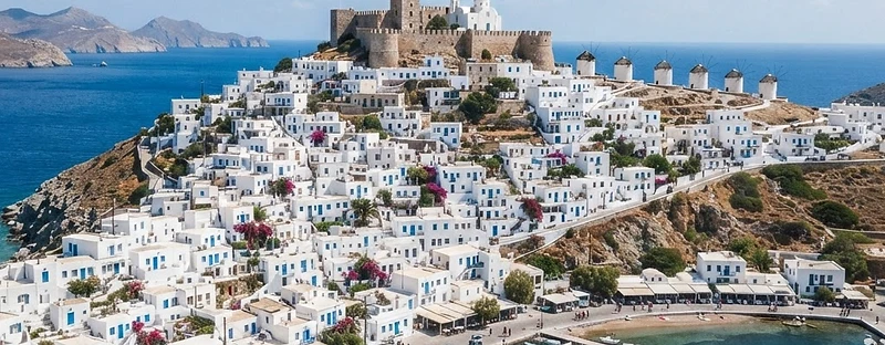 The white hill town of Astypalea Chora crowned by its Venetian castle, with the port below and the sea either side.
