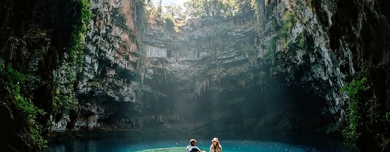 A rowing boat on the turquoise underground lake of Melissani cave, lit from the opening above.