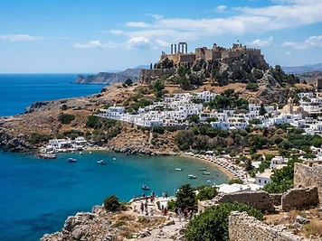 Ancient columns on the acropolis rock above the whitewashed village and bay of Lindos.