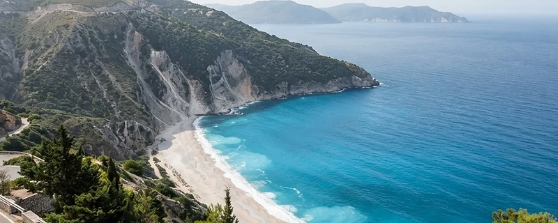 A crescent bay of turquoise water below white limestone cliffs on Kefalonia.