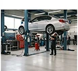 A clean well-lit auto shop bay with a car on a lift