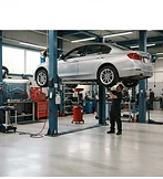 A clean well-lit auto shop bay with a car on a lift