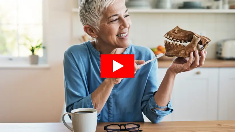 Smiling woman holding an old fossil jaw and a toothbrush in her kitchen