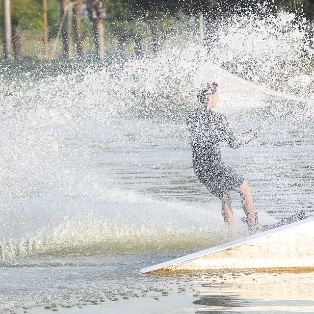ספורטאי גולש על מים בביצוע תמרון מרהיב ב-LAKE- TLV פארק דרום תל אביב, כשהוא מוקף בהתזות רסס דרמטיות. השימוש במהירות תריס גבוהה של 1/5000 שניות הקפיא את טיפות המים בדיוק רב, בעוד הקומפוזיציה מדגישה את הדינמיות של הרגע ואת האינטראקציה העוצמתית של הגולש עם המים והמתקן.