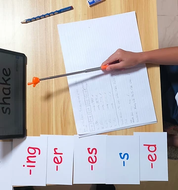 Child practising suffixes with word cards