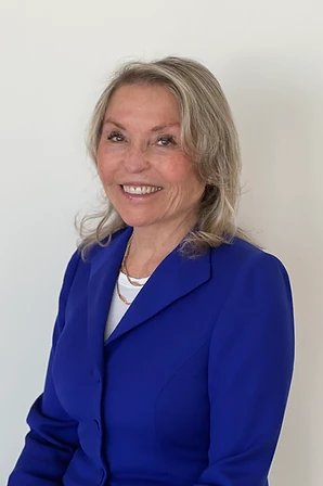Dr. Lilli Friedland in a royal blue jacket, smiling in front of a light background.