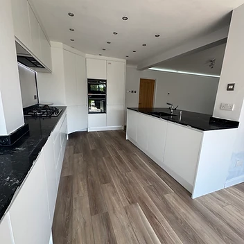 Completed modern white kitchen with dark stone island, UC-Homes.