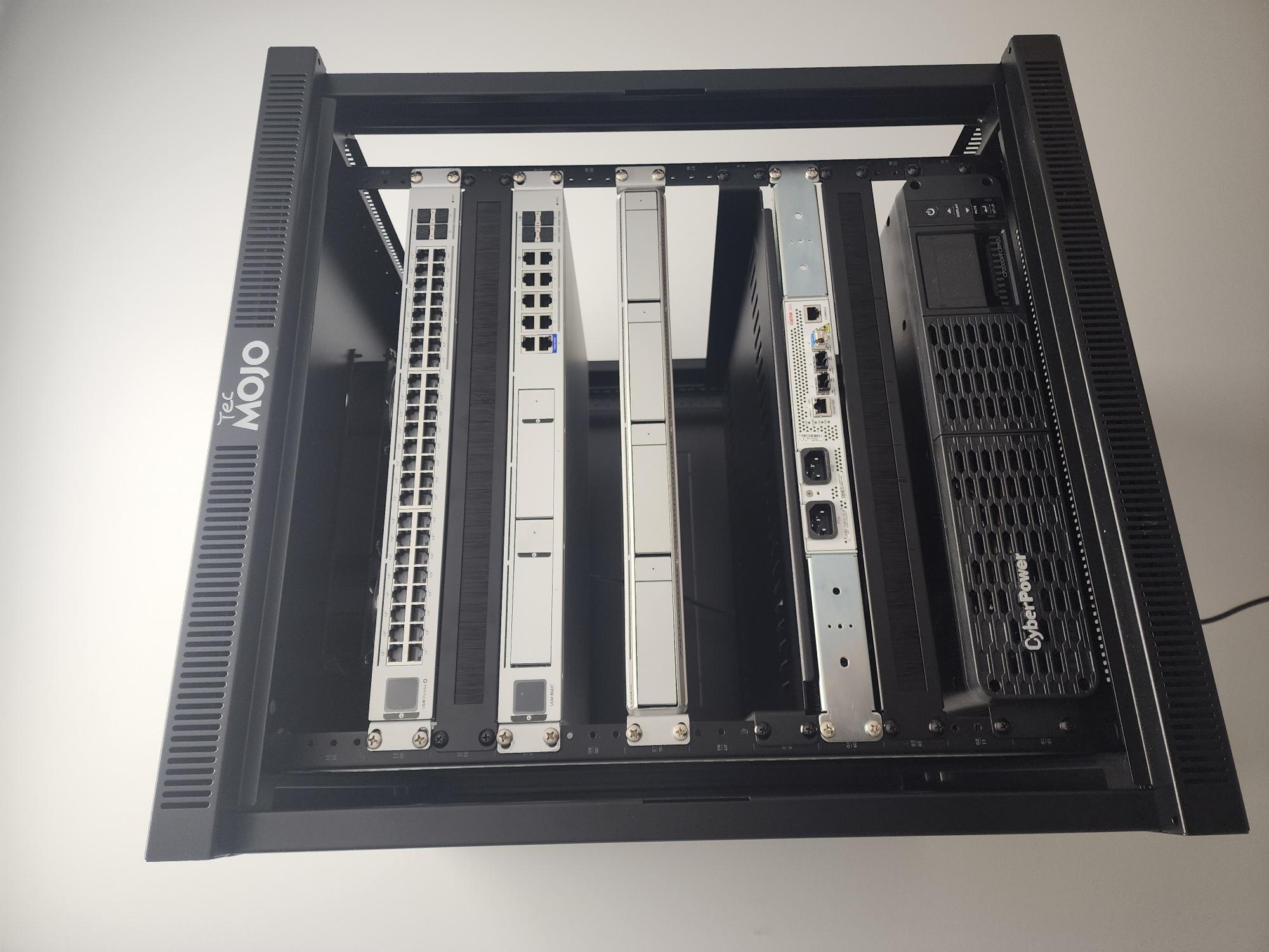 Front view of a black TecMOJO rack populated with a Ubiquiti 48-port switch, a UniFi gateway, a blanking panel, and a CyberPower UPS