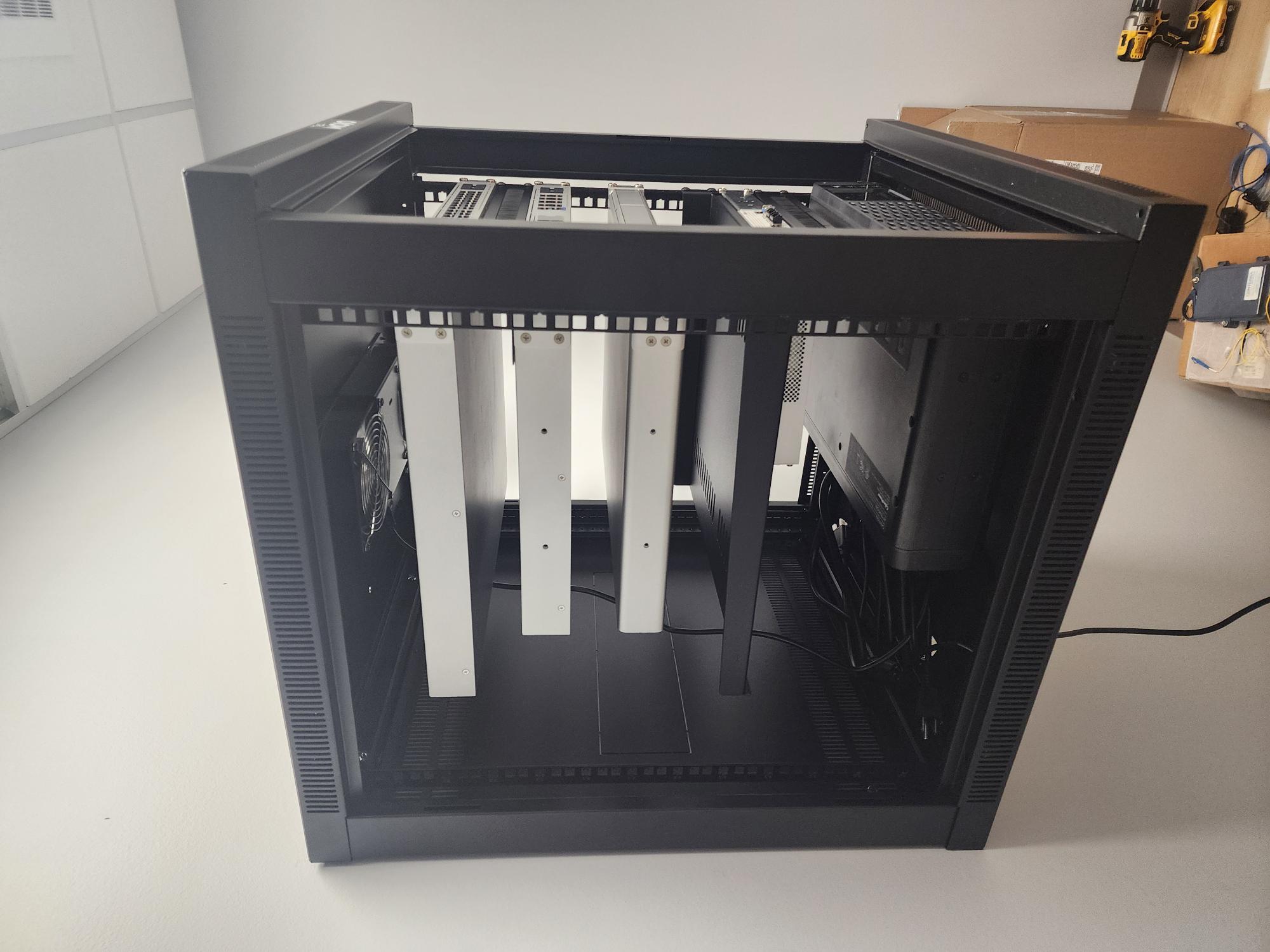 High angled view into a populated black TecMOJO wall-mounted rack showing networking equipment and a CyberPower UPS