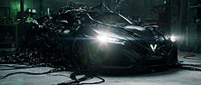 Glossy black symbiote-like liquid assembling a sports car in a dark garage, headlights switching on