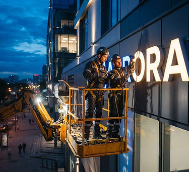 Technicians installing an illuminated storefront sign at dusk