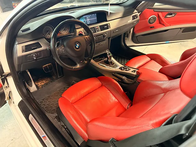 BMW interior with red leather front seats, black dashboard and centre console, viewed through the open door.
