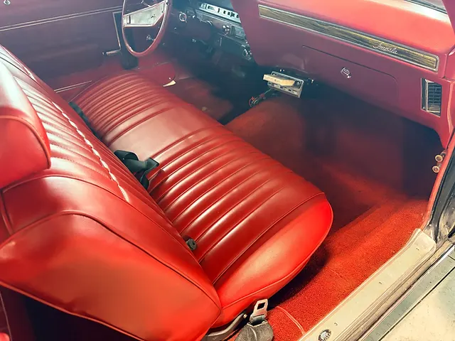 Classic Chevrolet Impala interior with a red bench seat, red carpet and red dashboard.
