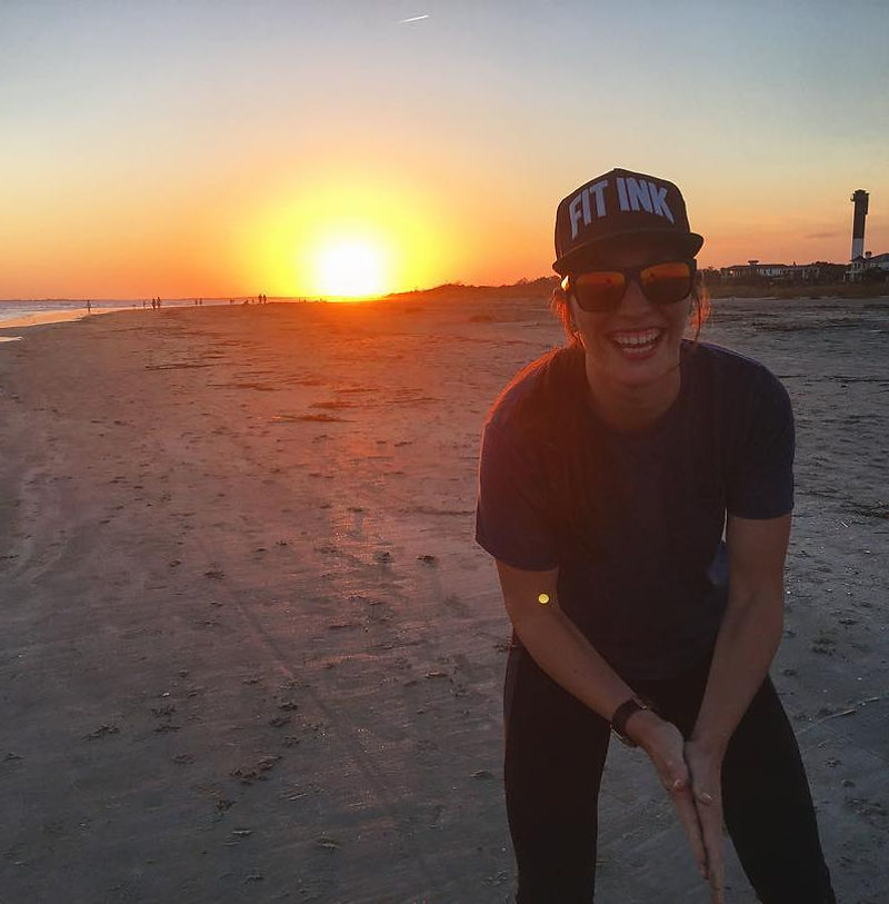 Lacie smiling on a beach at sunset, backlit by golden light