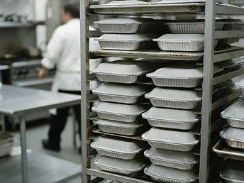 Rows of stacked lidded meal trays on a rolling rack in the kitchen