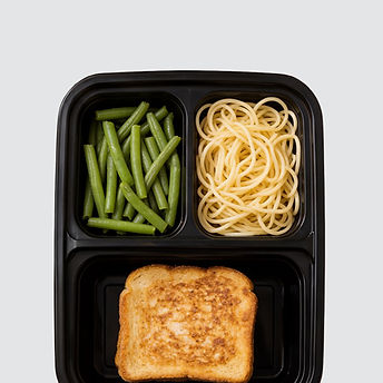 Top-down view of a three-compartment meal tray with green beans, spaghetti, and a grilled cheese toast