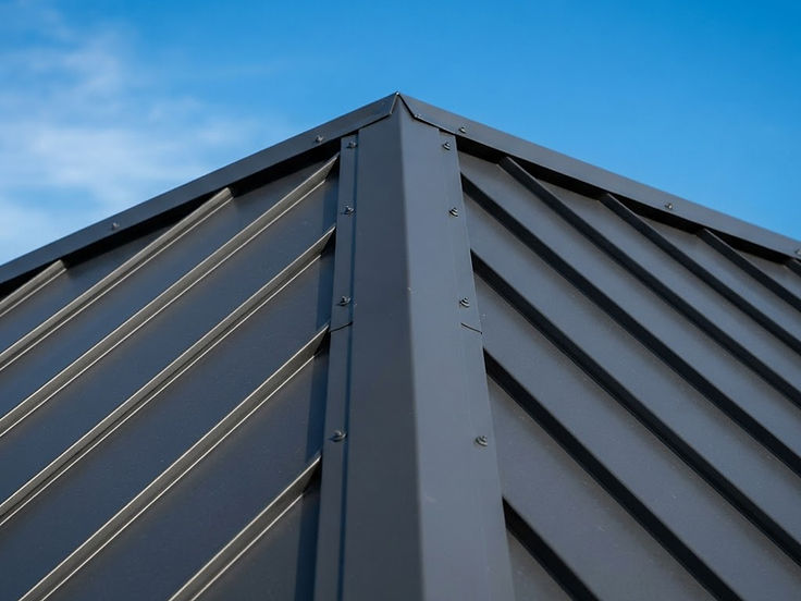 Close-up of charcoal standing seam metal roof panels and ridge cap