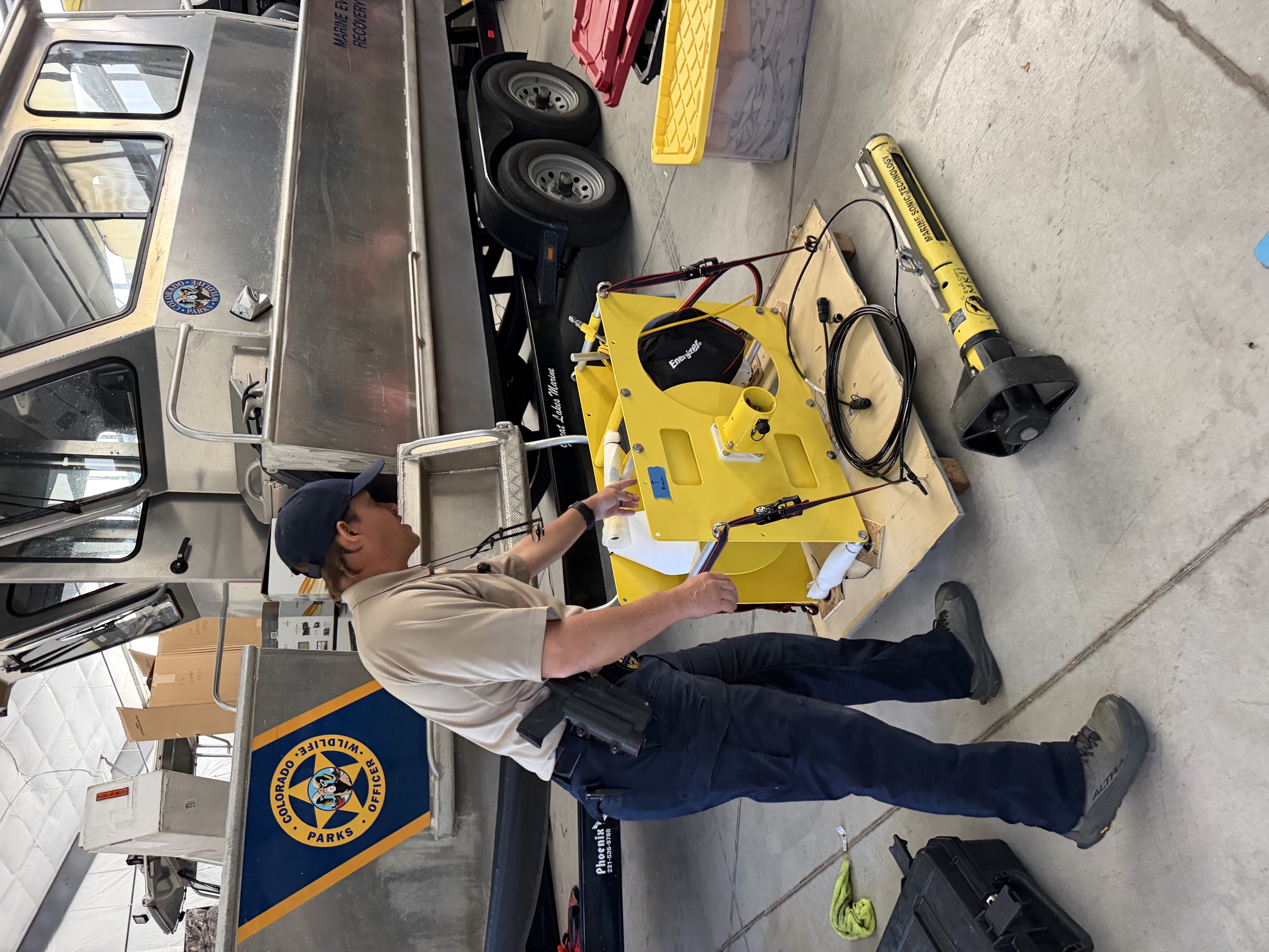 Colorado Parks & Wildlife officer with aquatic recovery equipment beside a CPW boat