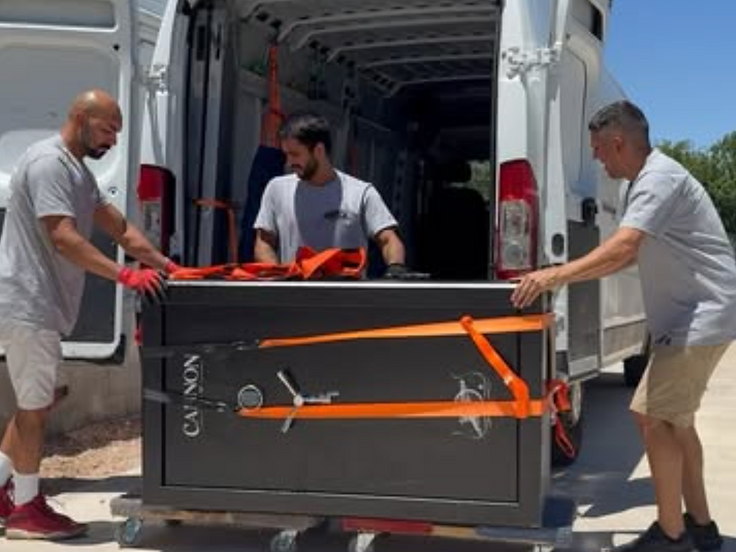 JSL Transport crew securing a heavy safe on a dolly at the van