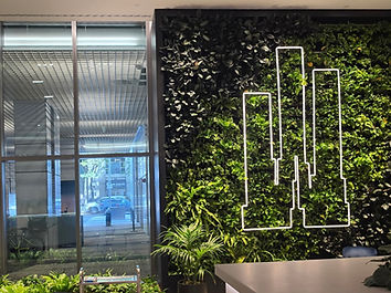 Modern commercial lobby with living plant wall and neon skyline art