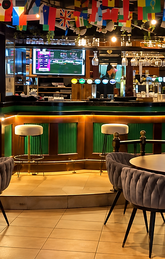 The bar area at Shakespeare Gastropub with warm lighting, international flags and sports screens