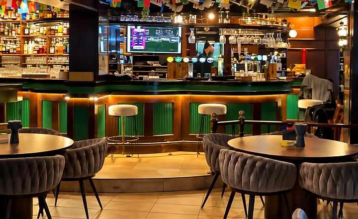 The bar area at Shakespeare Gastropub with warm lighting, international flags and sports screens