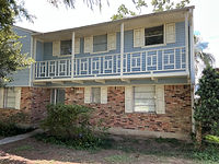 Two-story home with blue siding, brick exterior and a covered balcony