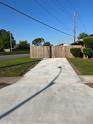 New concrete driveway extending from the street to the wooden gate.