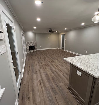 Renovated open-plan living room with wood-look flooring, recessed lighting, a fireplace and a kitchen island