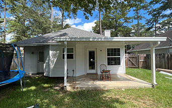 Rear exterior with finished white siding and a patio cover supported by white posts.