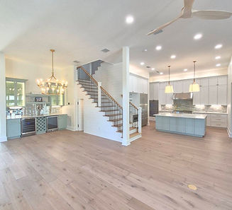 Open-plan home with white kitchen cabinets, a pale green island and matching beverage bar