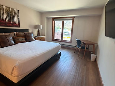 Freshly cleaned and staged guest bedroom with white bedding, forest artwork, and wood flooring — professional housekeeping result by Elite Property Management