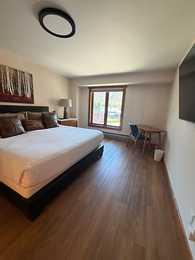 Freshly cleaned and staged guest bedroom with white bedding, forest artwork, and wood flooring — professional housekeeping result by Elite Property Management