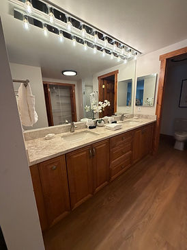 Cleaned master bathroom with marble vanity, Edison bulb lighting, and fresh white towels — professional housekeeping result by Elite Property Management