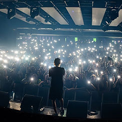 Artist facing a phone-lit crowd at 170 Russell