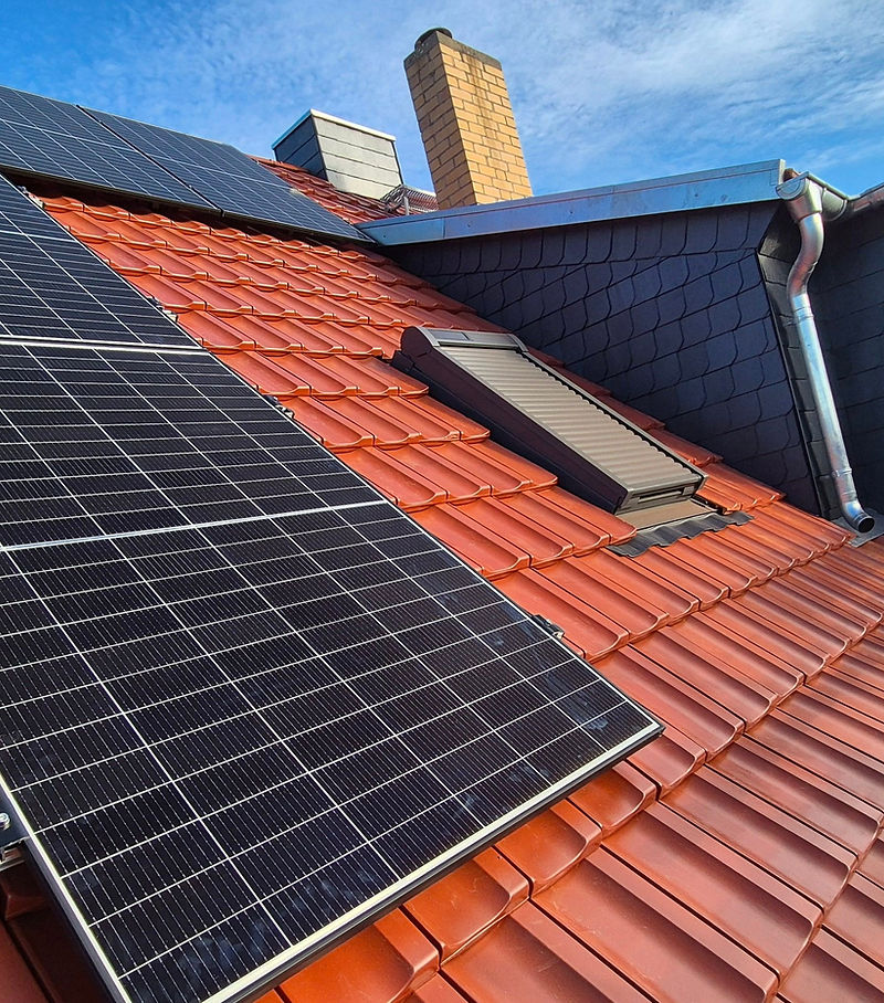 Steildach mit Ziegeln und Solarpanelen, Dachfenster und Schornstein