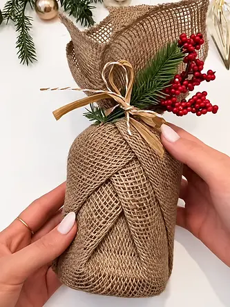 Burlap style fabric gift wrap tied with ribbon and botanical decorations