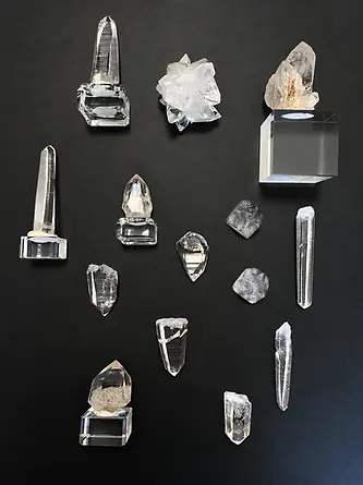 Polished crystal points and clusters on acrylic stands, arranged on a black background