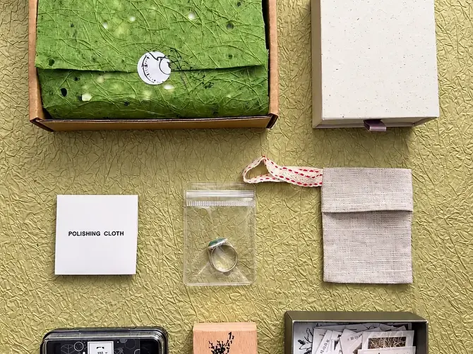 Kraft mailing box with a green paper-wrapped jewelry set and coordinated packing accessories
