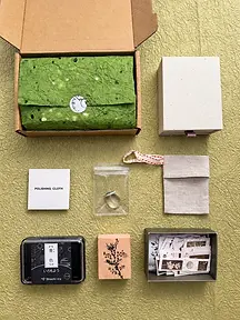 Kraft mailing box with a green paper-wrapped jewelry set and coordinated packing accessories