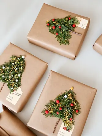 Kraft wrapped gifts with small tree decorations and paper tags