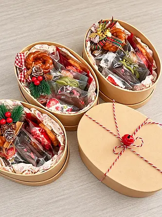 Open oval kraft gift boxes with treats and paper filler