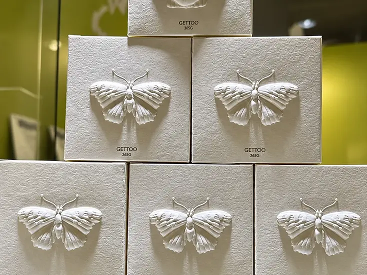 Paperboard cartons with butterfly and shell decorative finishes