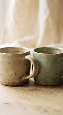 Deux tasses en céramique posées côte à côte sur une table en chêne