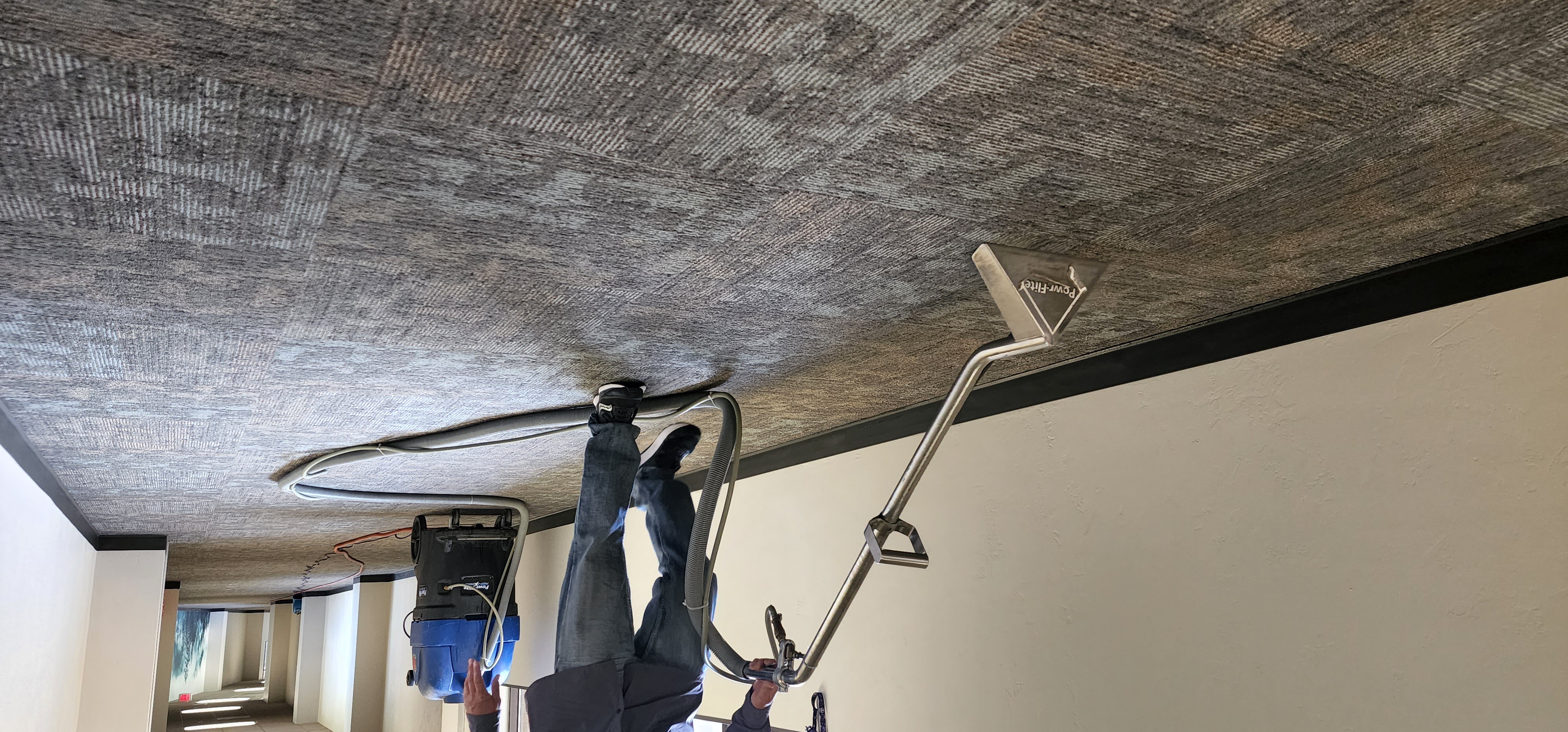 Worker using a carpet extraction machine on a hallway carpet